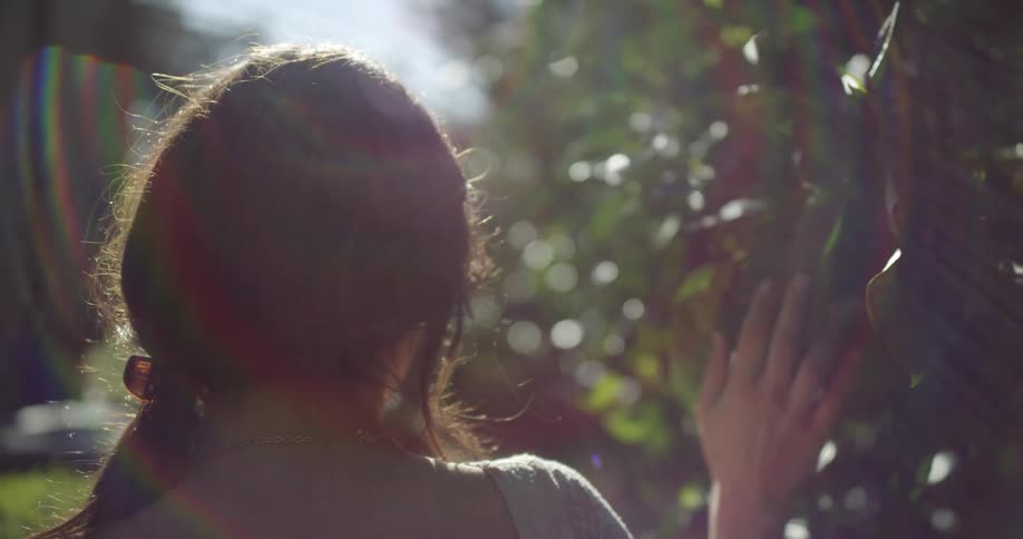 A woman walking down a path touching bushes