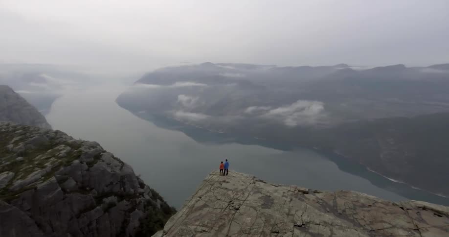 Two people stand near a cliff