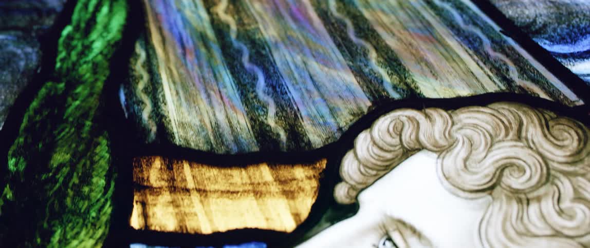 Light shines through colorful stained glass window with religious image