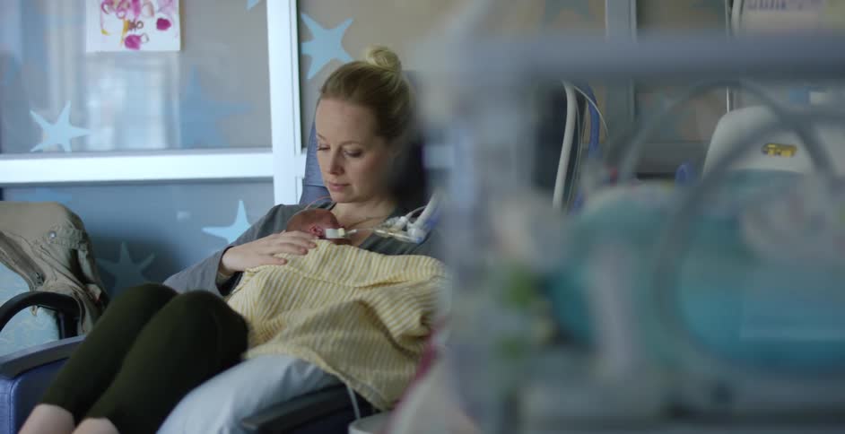Young woman holding a newborn baby laying on a hospital bed
