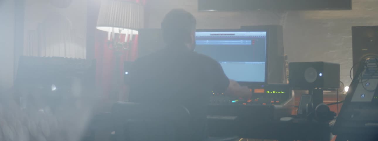Man working on a mixing console inside a sound studio