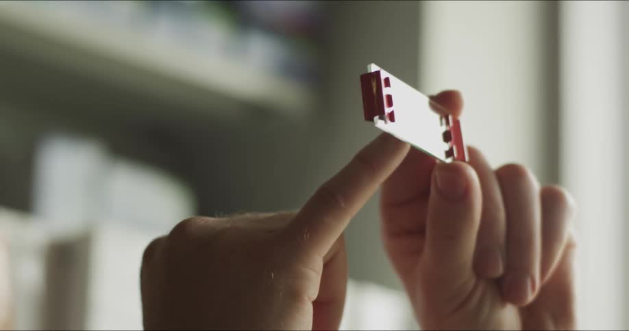 Mans hands hold up a microscope slide