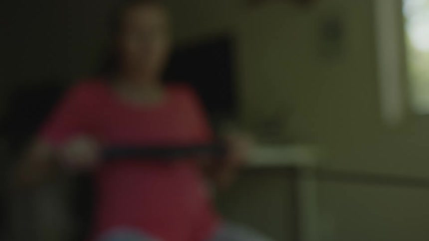 Young fit woman exercising on a static rowing machine at home