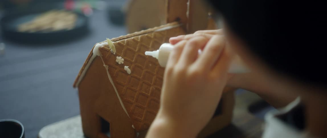 Children sitting by a table making gingerbread houses