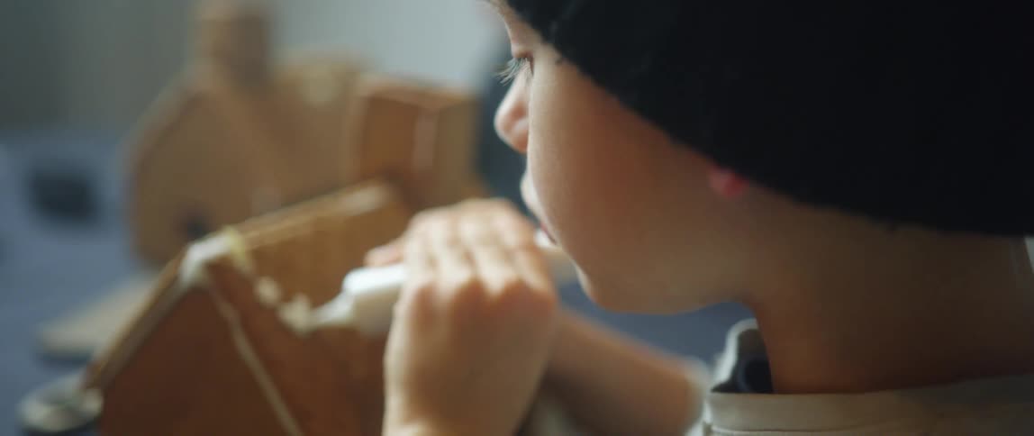 A child decorating a gingerbread house