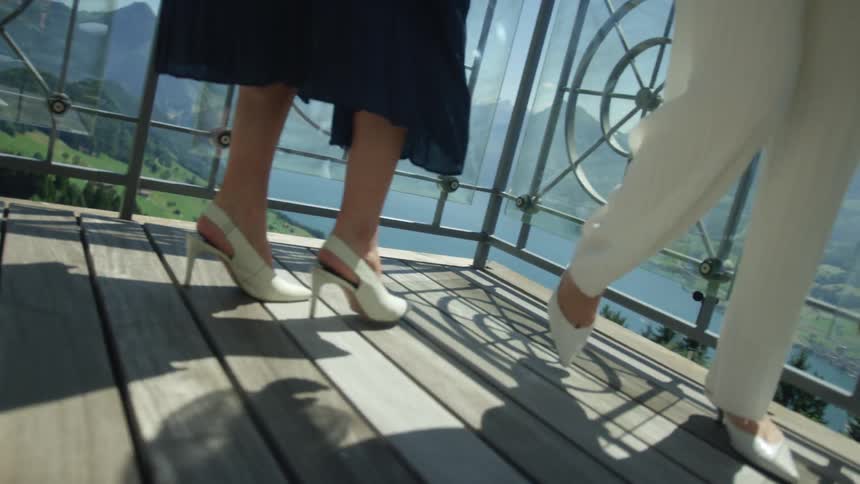 Two women walk on a patio above the shore