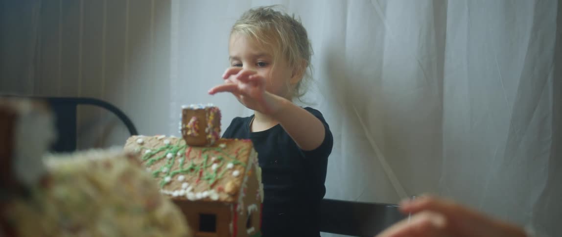 A child playing with a gingerbread house