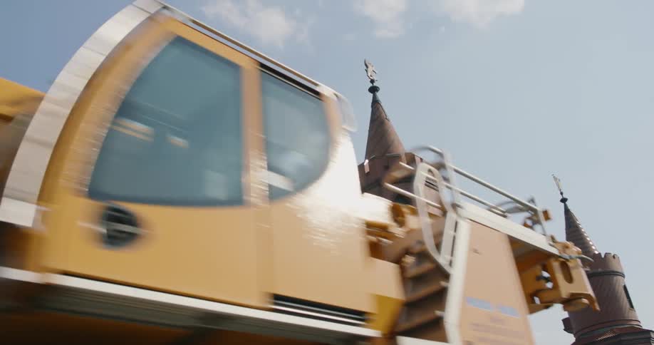 Yellow construction crane parked in front of a castle