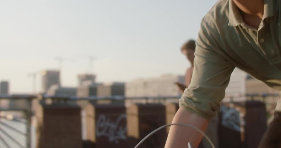A man bikes across a bridge with pedestrians walking on it