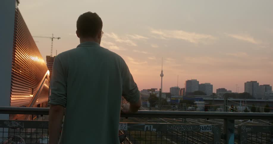 A man stands on a bridge and looks at the skyline