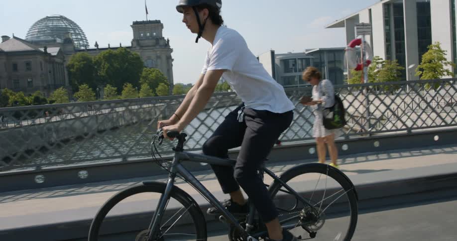 A man biking across a city bridge