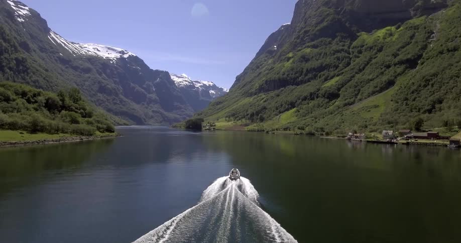 A boat moves faster over a lake between a mountain range