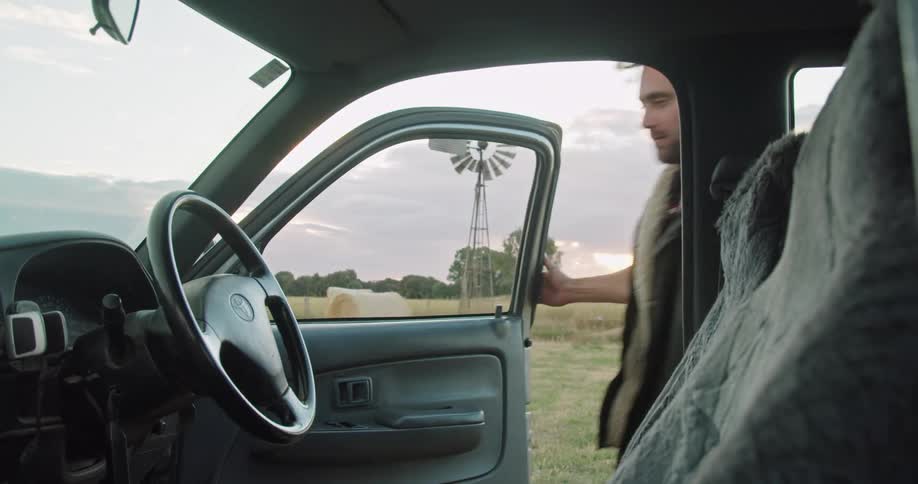 A man is getting into a car in a rural area