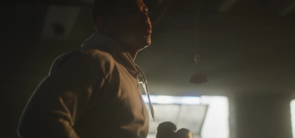 A man jogs in a dark room illuminated only by light from an open window