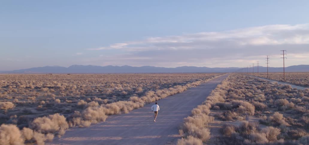 Person running down empty rural road on a cloudy day