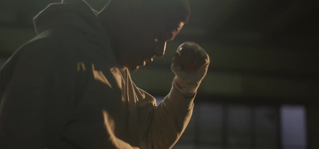 Young boxer concentrates after training inside an abandoned warehouse at sunset