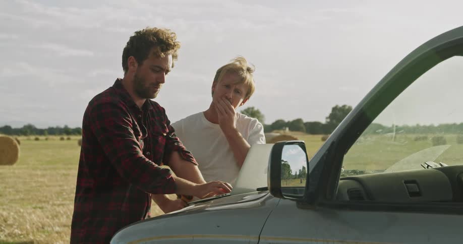 Two men looking at a laptop together at a farm