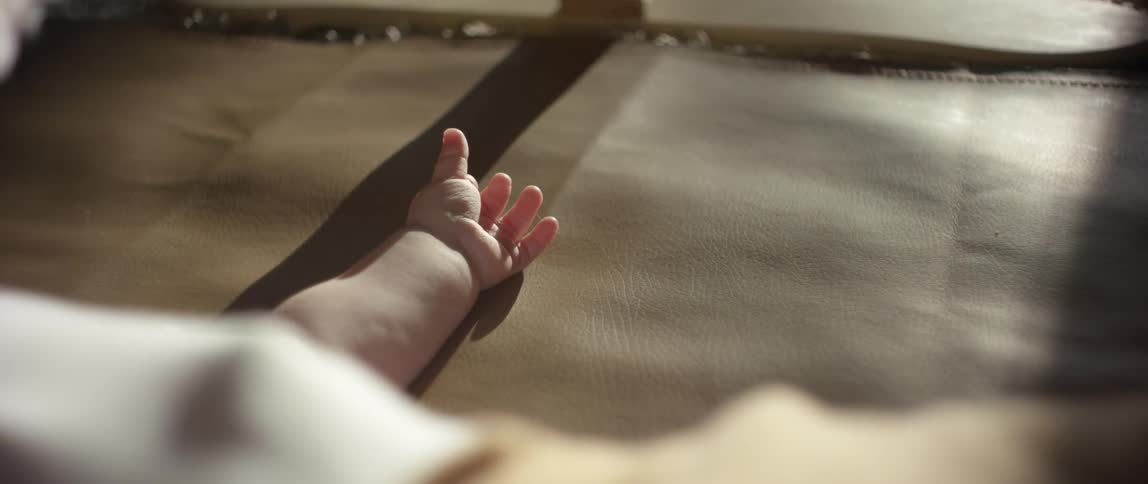 Toddler lying in shadow cast by sunlight reaches up
