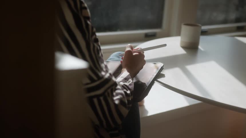 A person is taking notes by the window