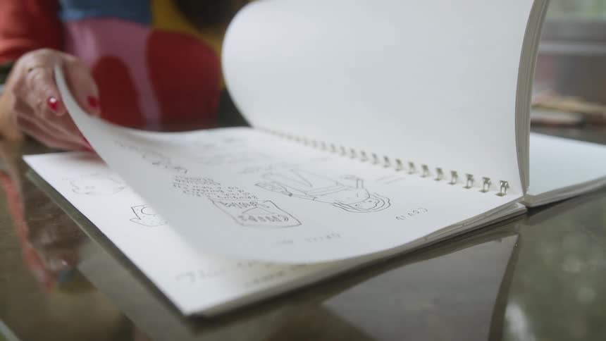 Woman looking at the drawings on a notebook over a table at home