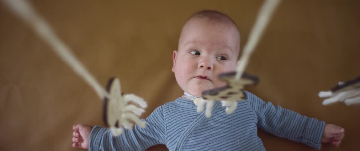A baby is lying underneath a mobile