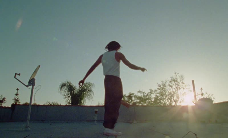 A black man dances on an outdoor basketball court with the sun setting