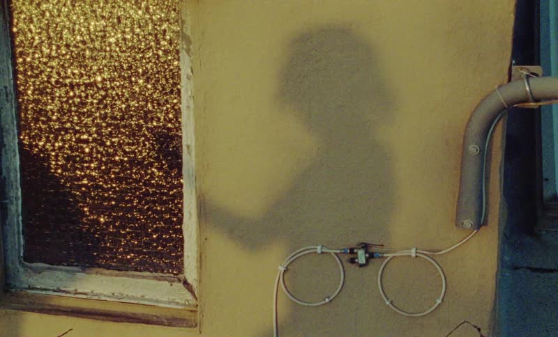Shadow of person dancing can be seen against wall near window