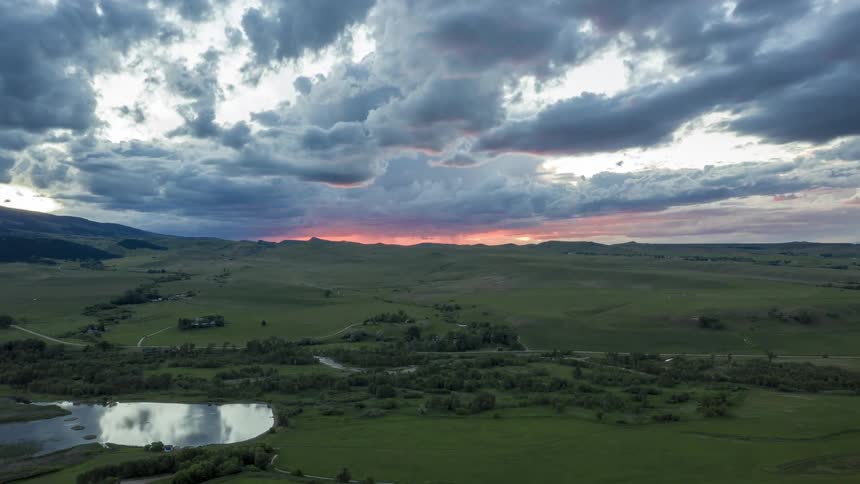 An aerial view of clouds over a grassland with a river running through it