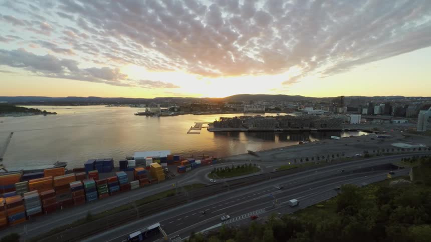 An ocean harbor next to a freeway at sunset