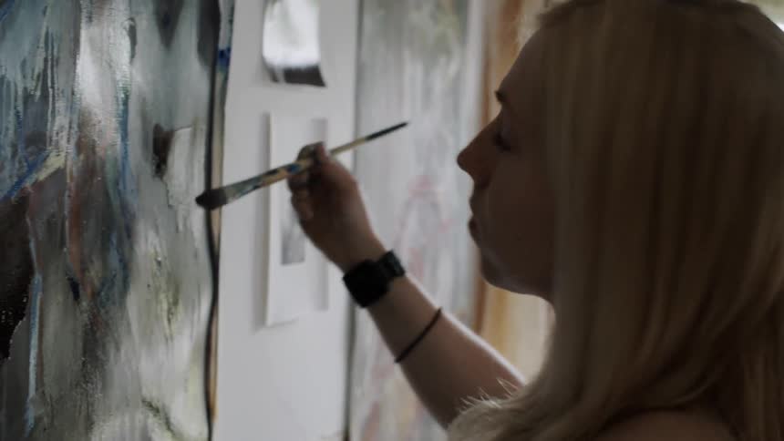 A woman is painting and looking around