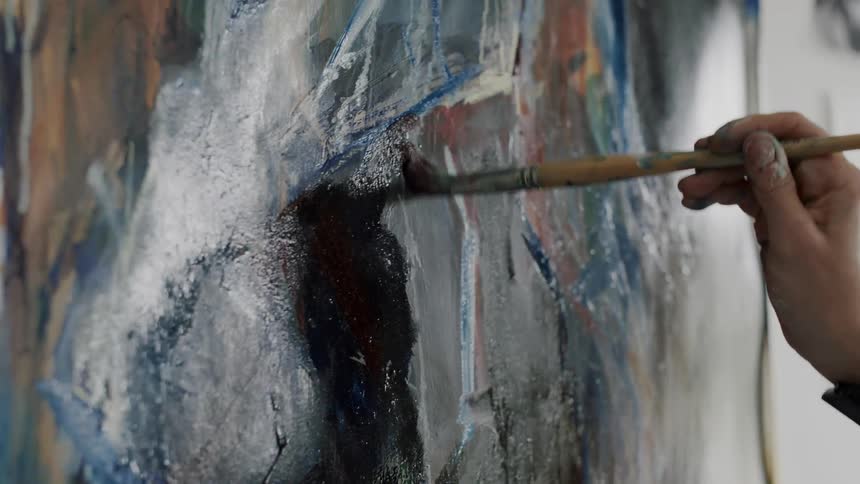 A person paints on canvas using a brush