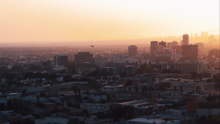 The setting sun illuminates a foggy metropolis
