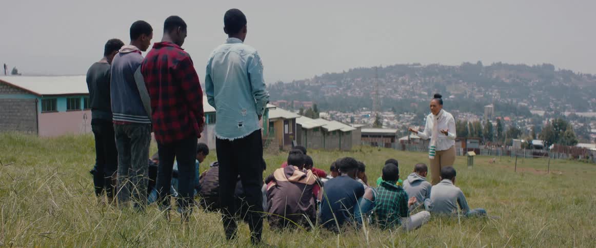 A group of people in a third world city pray in a field outside