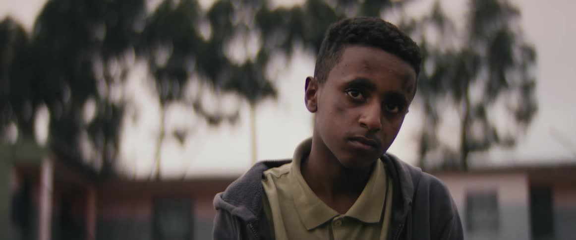 A boy sits outside holding a watch