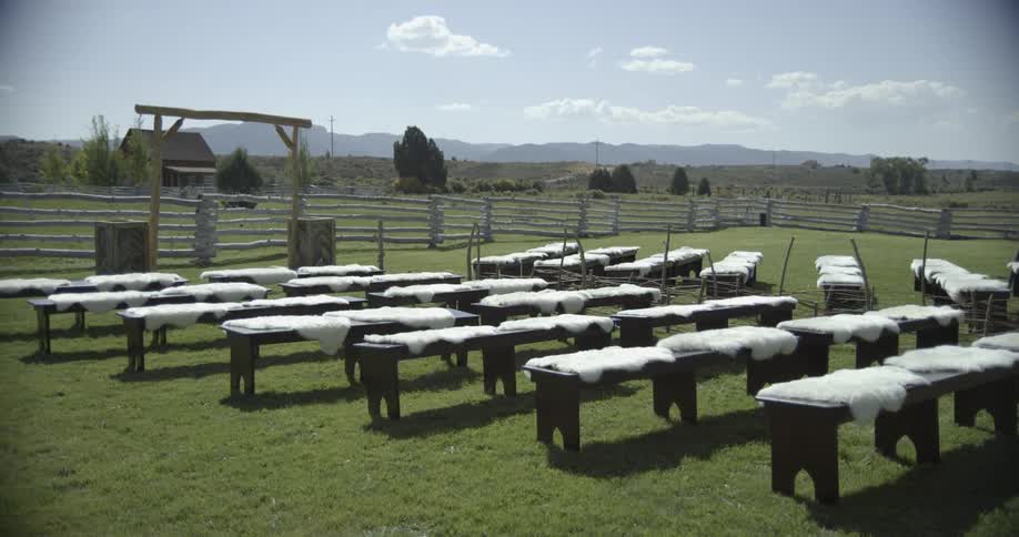 Tables with white pelts drying outdoors in a corral on a sunny day