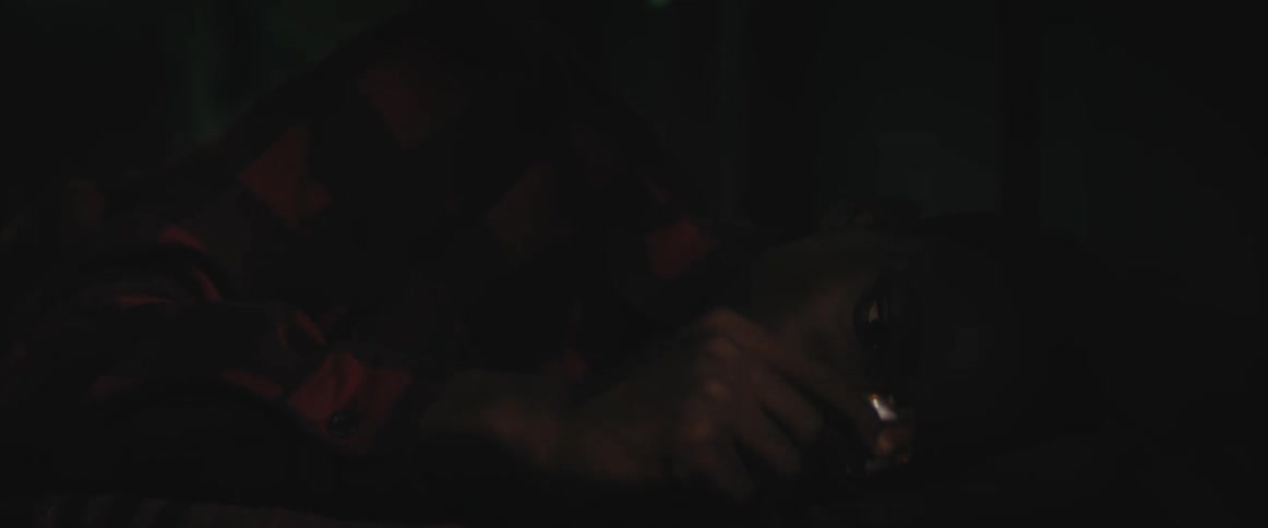 A young man lies in bed and runs his fingers along a wristwatch that he places in his jacket