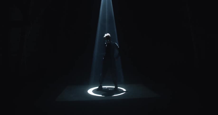 Young man standing inside a dark smoky room under a spotlight