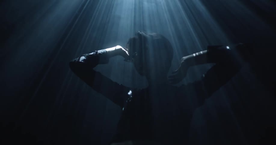 A man standing under a strobing spotlight