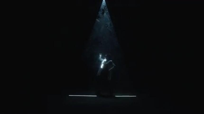 Person posing standing under a triangular lighting in a dark setting