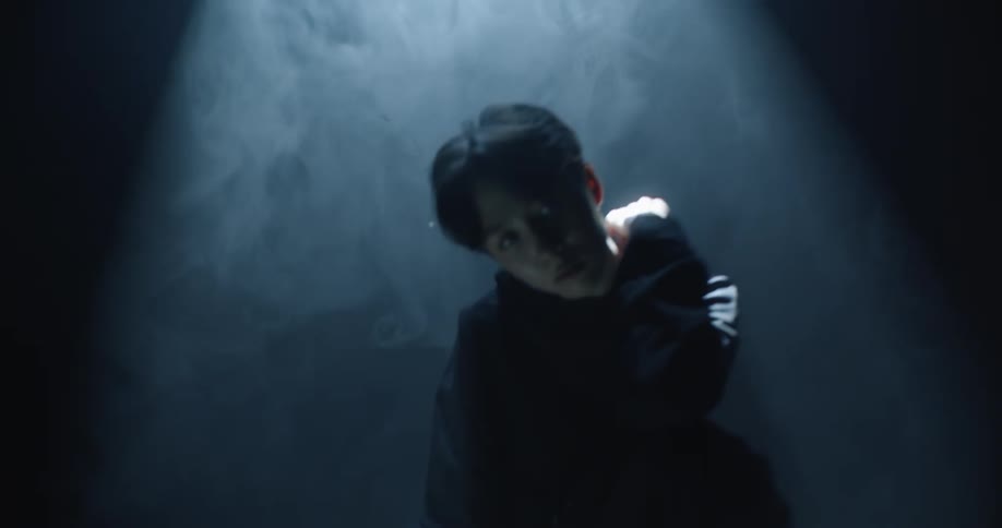 A teenage girl stands under a spotlight and on a lit up triangle