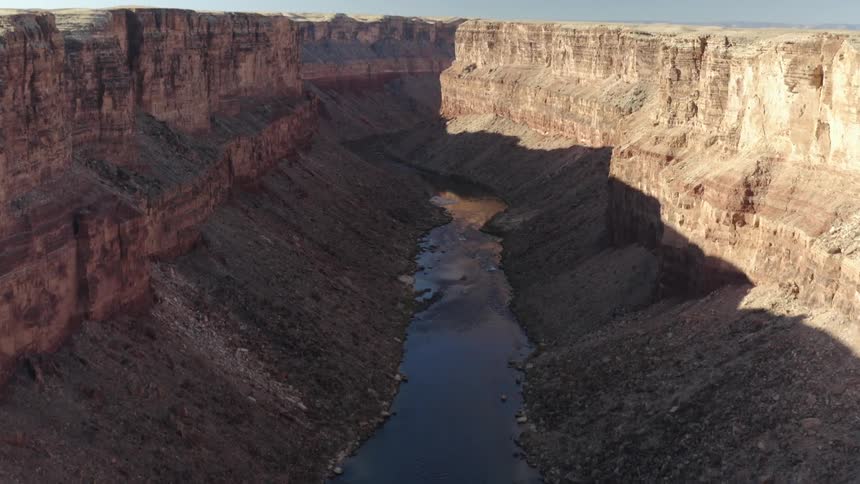 A small creek runs through the valley of a narrow canyon with a plateau all around