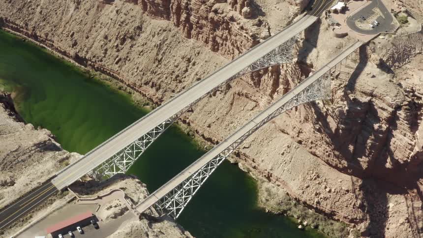 Aerial view of two bridges over the green waters of a river in a canyon