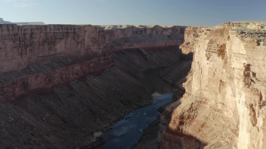 Shadow covers river running through canyon on misty day under clear sky