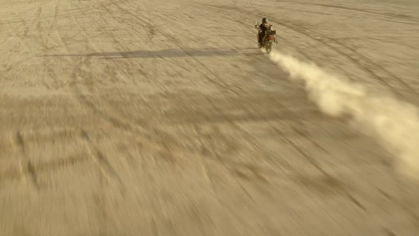 Multiple motorbikes driving down a dusty road