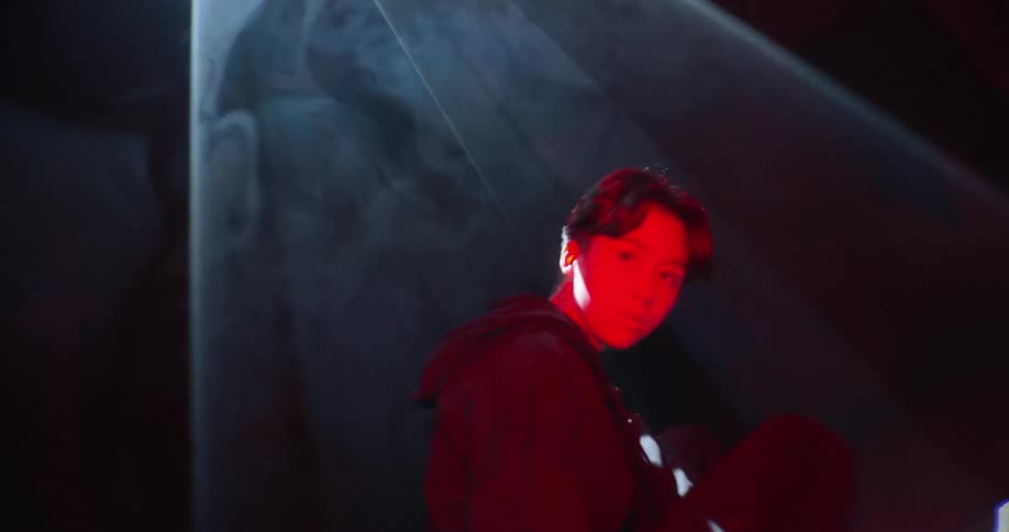 Woman with a red light projecting on her face with strobing white flashing lights beaming down on her