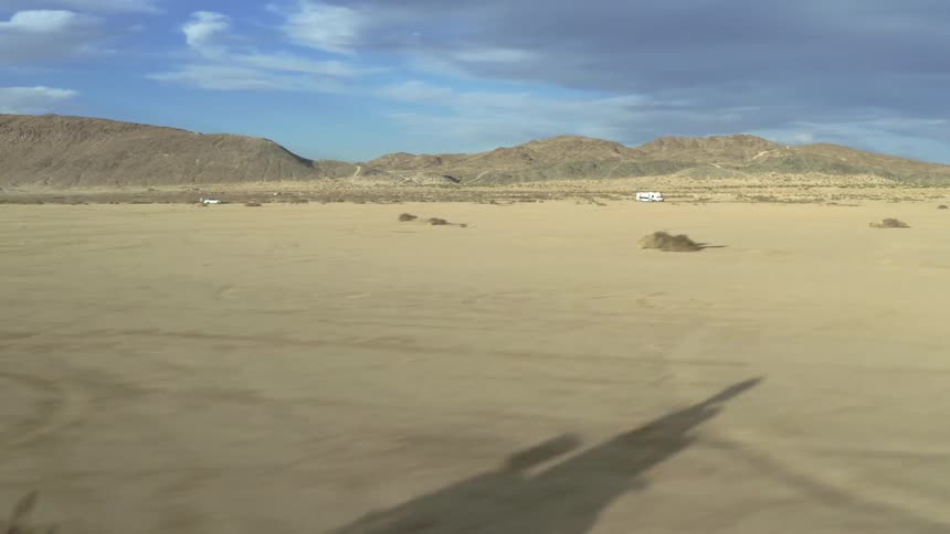 Two motorcyclists race side by side through a vast desert