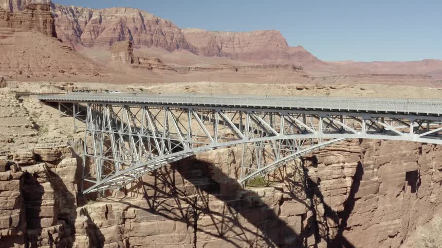 A pair of bridges spanning an arid canyon under a clear daytime sky