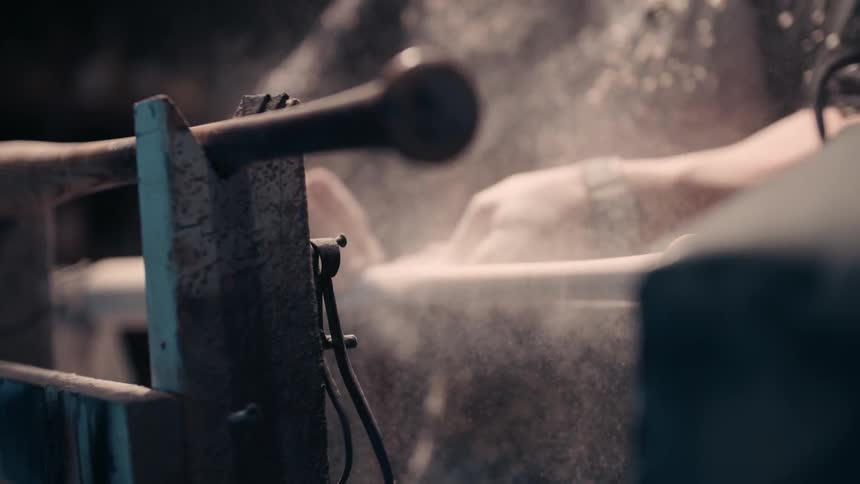 A person is shaving a bat on a machine