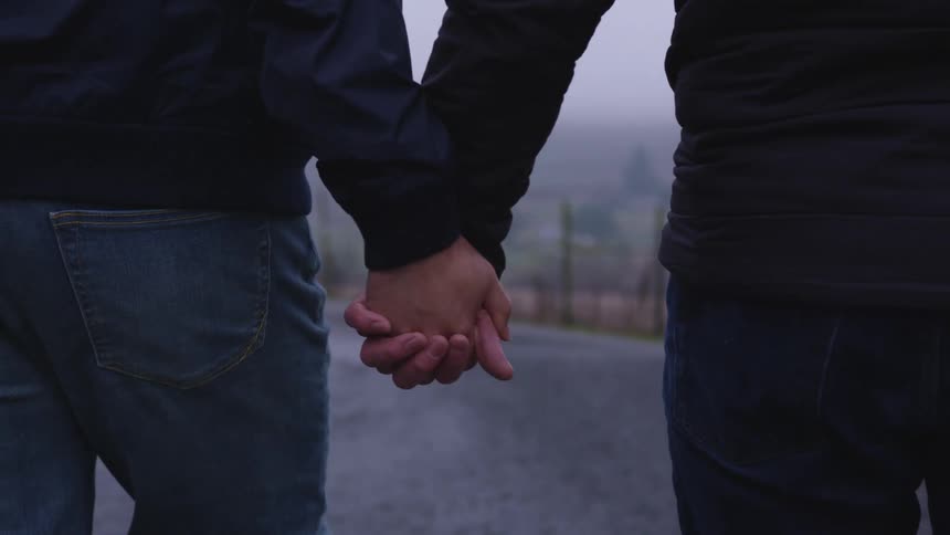 Couple holding hands walking down a road in a rural area