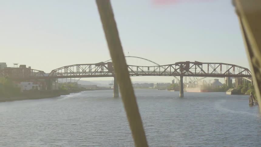 A bridge over the water with construction cranes on the shore